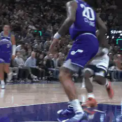 Basketball player dunks over defender