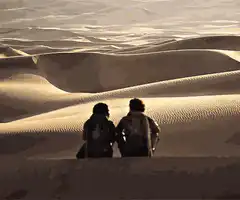Two people sitting on sand dunes