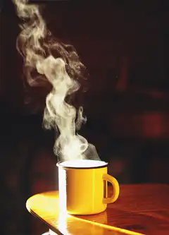 Steaming yellow mug on wooden table