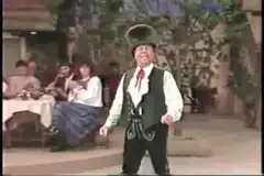 Man in lederhosen singing on stage