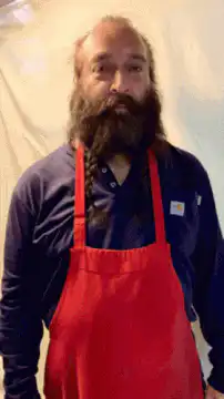 Bearded man in red apron gestures and poses