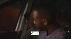 Man in car smiling with text 'SOON'