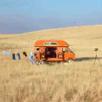 man hanging laundry near orange van