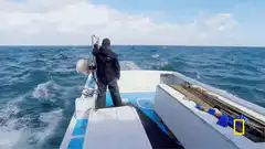 Man on boat holding railing in rough sea