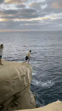 Man cliff jumping into ocean