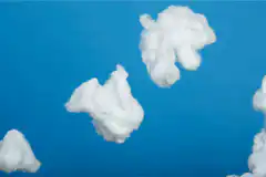 Hand throws paper airplane among cotton clouds