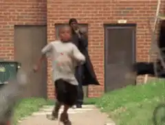 Man in trench coat walks past running boy