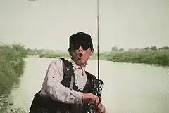 Man fishing with fish hitting face