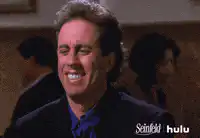 Jerry Seinfeld laughing and grimacing