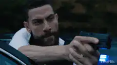 Bullseye aiming a gun from a car