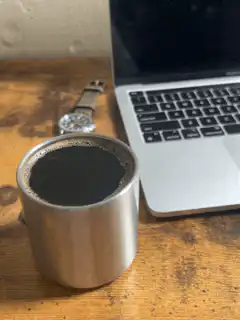 Coffee cup next to laptop on desk