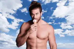 Shirtless man eating ice cream cone