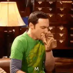 Sheldon coughing into a paper bag