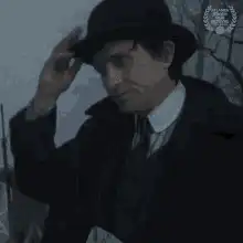 Man in hat tips and bows head