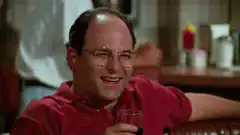 George Costanza laughing with a drink