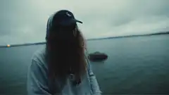 Person by water making hand gestures