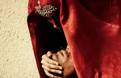 Woman in red veil kissing man's forehead
