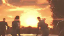 People watching a giant monster emerge from a sunset