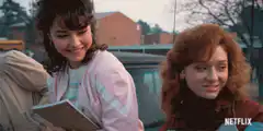Two girls talking by a car