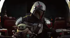 The Mandalorian holding Grogu
