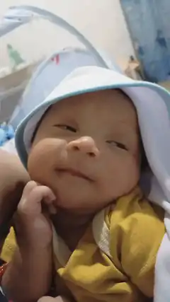 Baby in yellow shirt and white hat