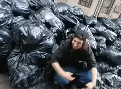 man sitting in garbage bags