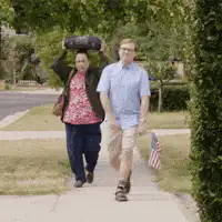 Man and woman walking with flag and tire