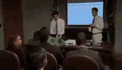 Ron and Leslie hold up signs in a meeting