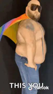 Bald man with rainbow cape and sunglasses