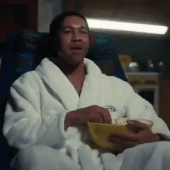 Man in bathrobe eating popcorn