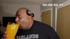 Man drinking orange juice from large glass