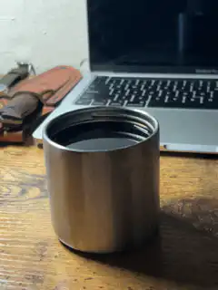 metal cup on wooden table near laptop