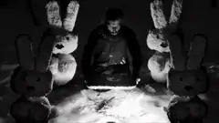 Man sitting with four large bunnies