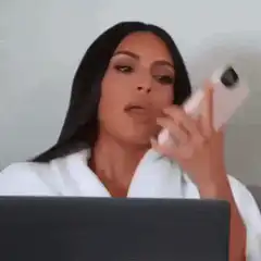 Kim Kardashian on phone looking at laptop