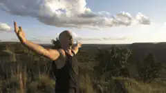 Man spreading arms wide on cliff