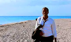 Man laughing on beach then jumping off boat