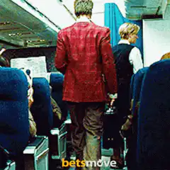Man in red jacket walks down airplane aisle