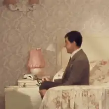 Man on bed throws pillow