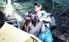 man in woods holding bloody axe and meat