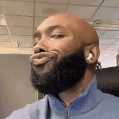 Man with beard and earbuds making a face