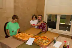 man and kids with two pizzas