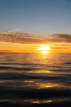 sunset over ocean with contrail