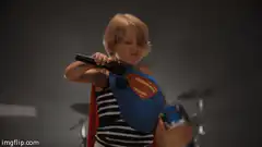Toddler Superman plays air guitar