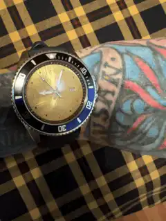 Gold and blue watch on tattooed arm