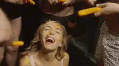 Blonde woman eating cheese puffs off face