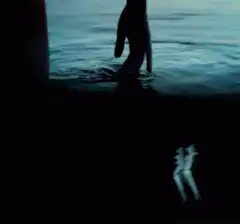 Hand touching water with reflection