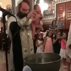 Priest baptizes baby in large metal tub