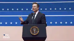 Elon Musk waves at podium