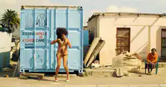 woman dancing in front of blue shipping container