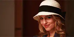 Blonde woman in hat smiles and turns